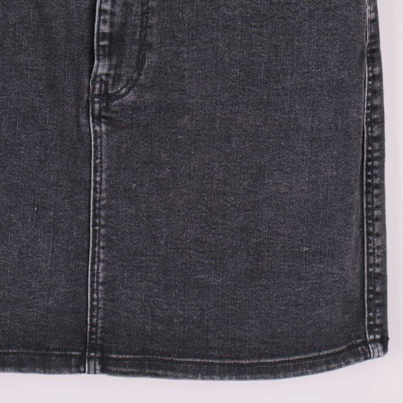 Närbild på nedre delen av svart denimkjol med synliga sömmar