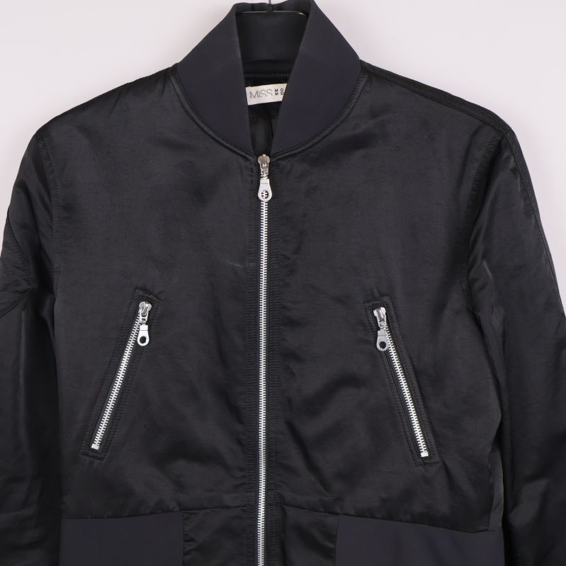 Detalj på jackans silverfärgade dragkedjor och överdel