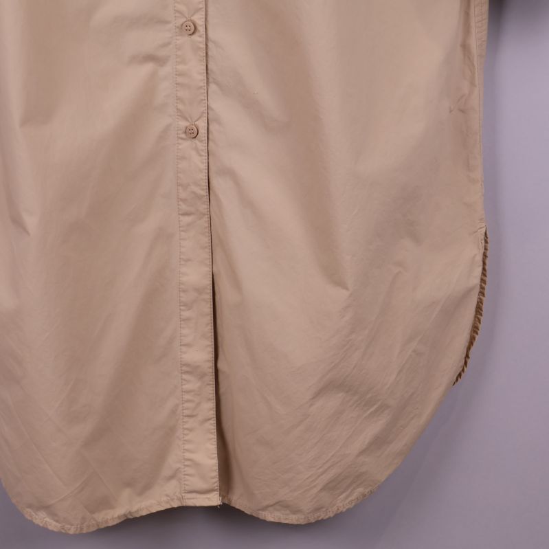 Närbild av rundad nederkant på beige skjortklänning