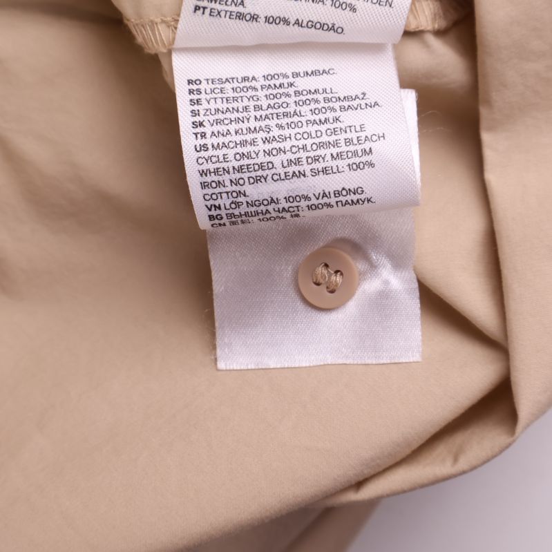 Detalj av etikett med extra knapp och text om material