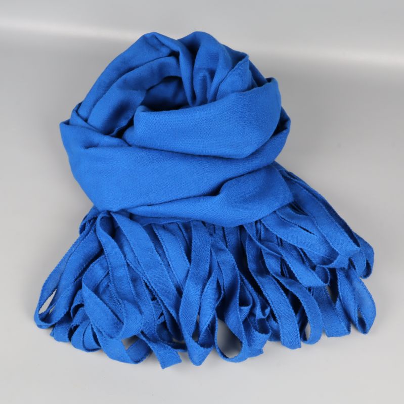 Sjal i blått tyg rullad och lagd med fransarna synliga