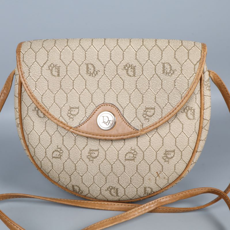 Närbild på väska med monogrammönster och knappstängning