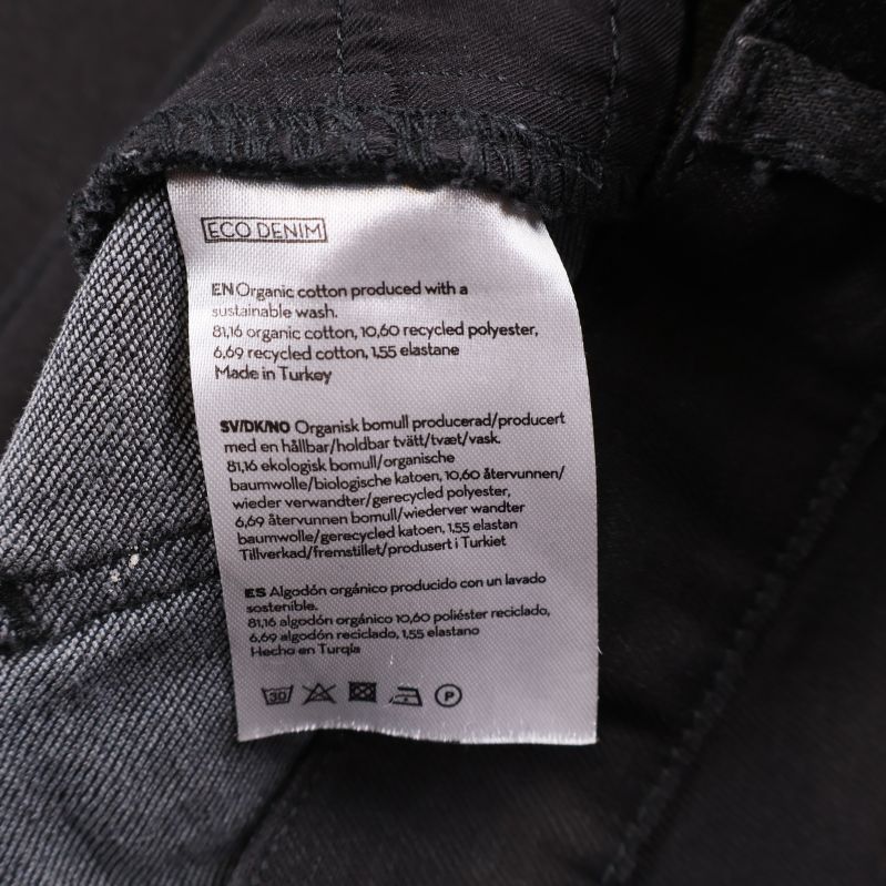 Tvättrådslapp med materialinnehåll inuti svarta jeans