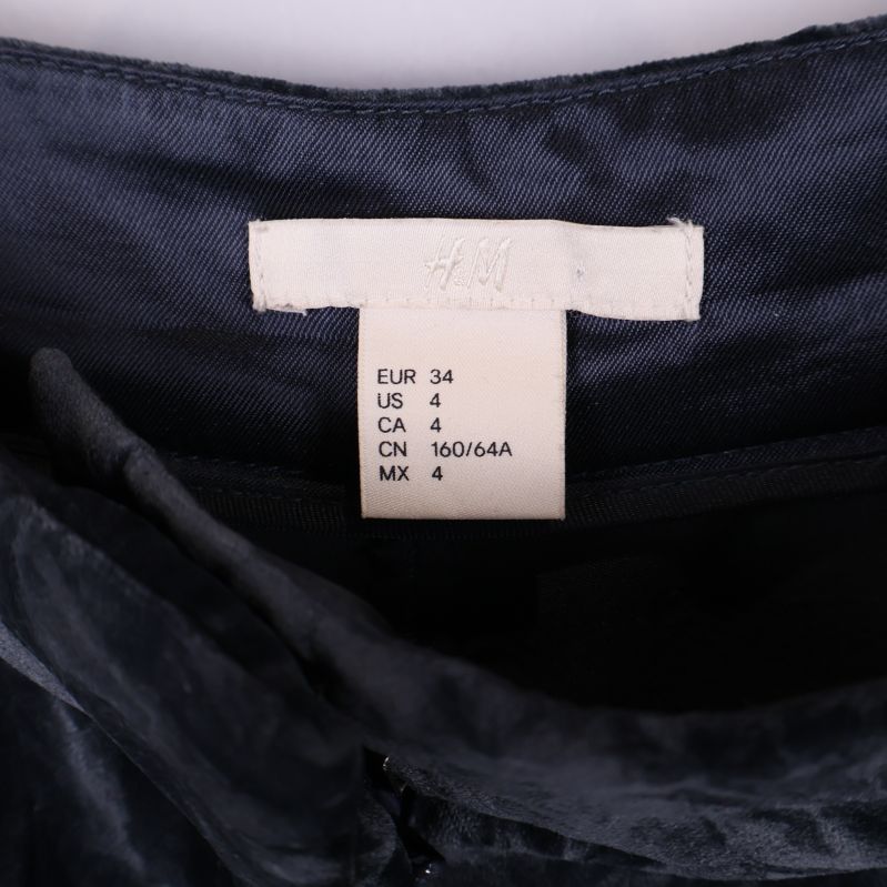 Närbild på storleksetikett för svarta byxor från H&M
