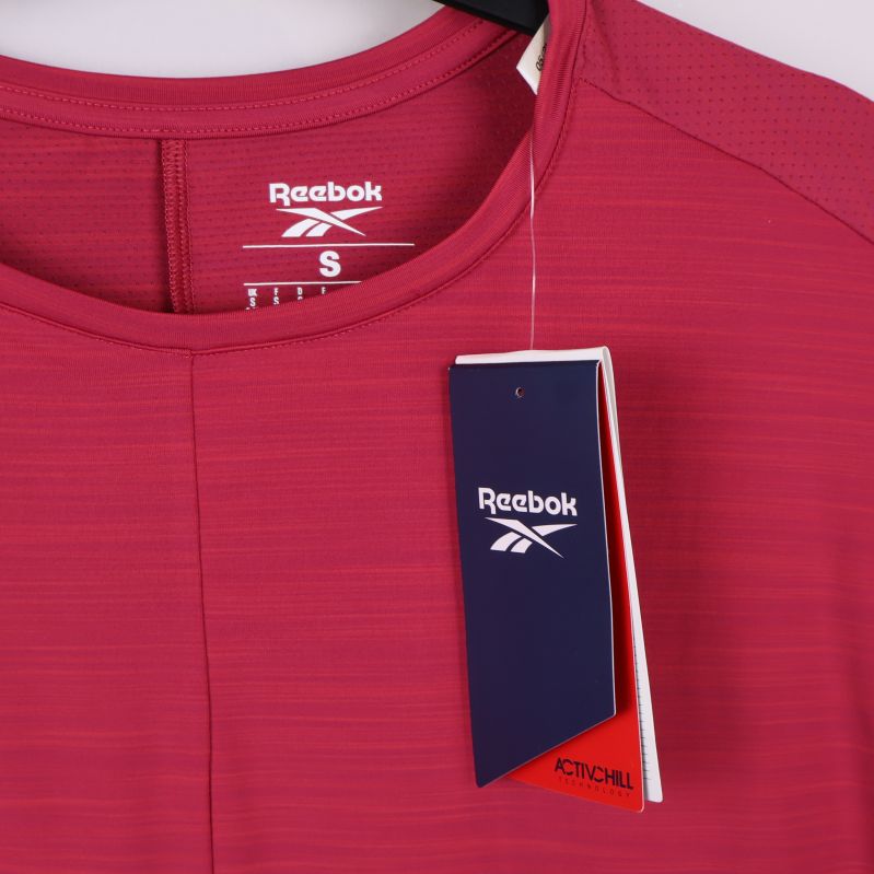 Närbild av halsringning och Reebok-logga på ceriserosa topp