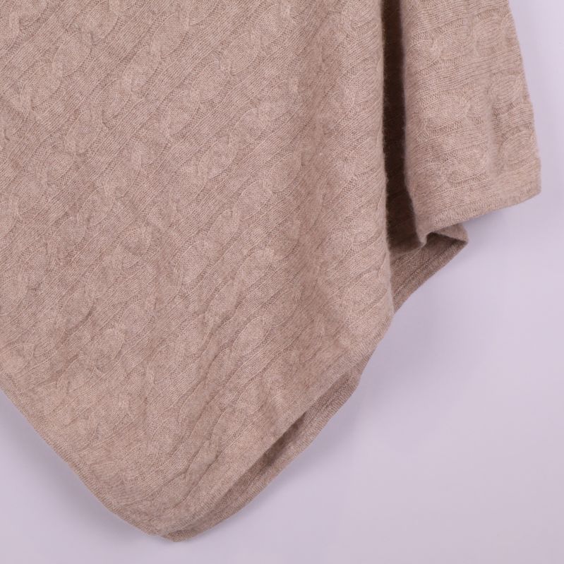 Kantdetalj på beige poncho visar textur och avslut