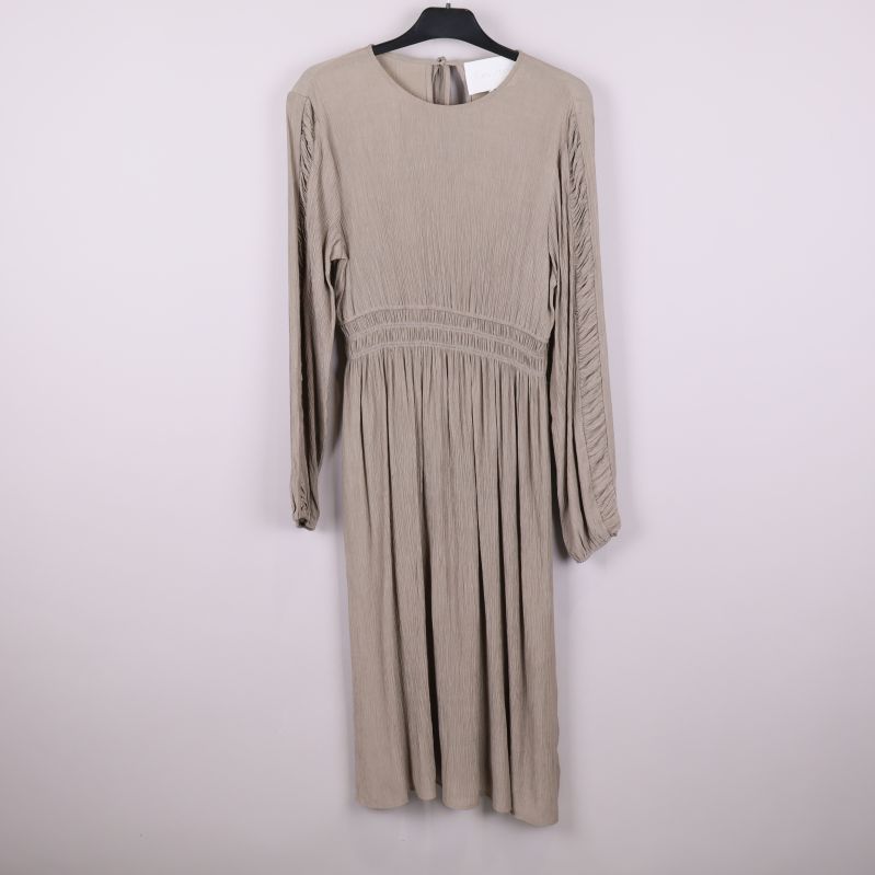 Helbild framtill av beige långärmad plisserad klänning