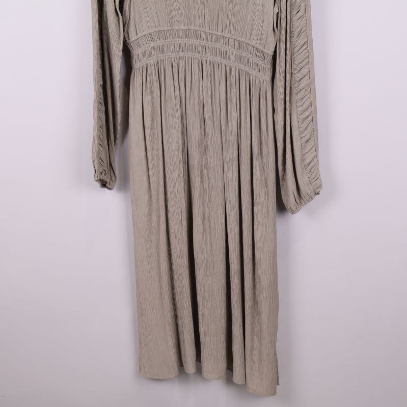 Nedre del av beige plisserad klänning