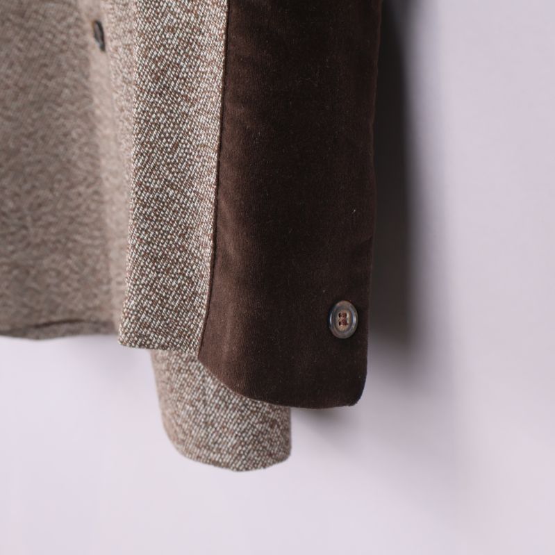 Närbild på ärm med brun sammetsdetalj och knapp