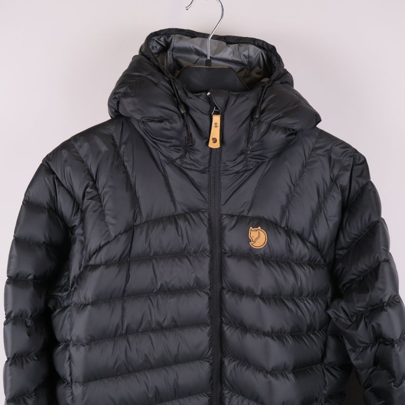 Närbild av jackans övre del med huva och logga