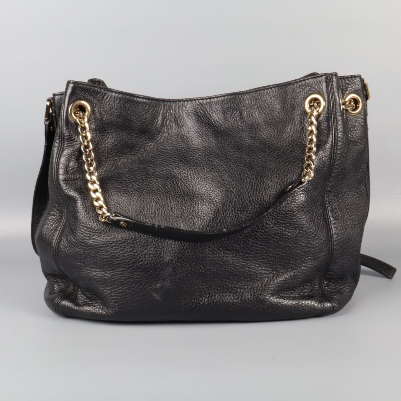 Framsidan av svart väska med guldkedjehandtag