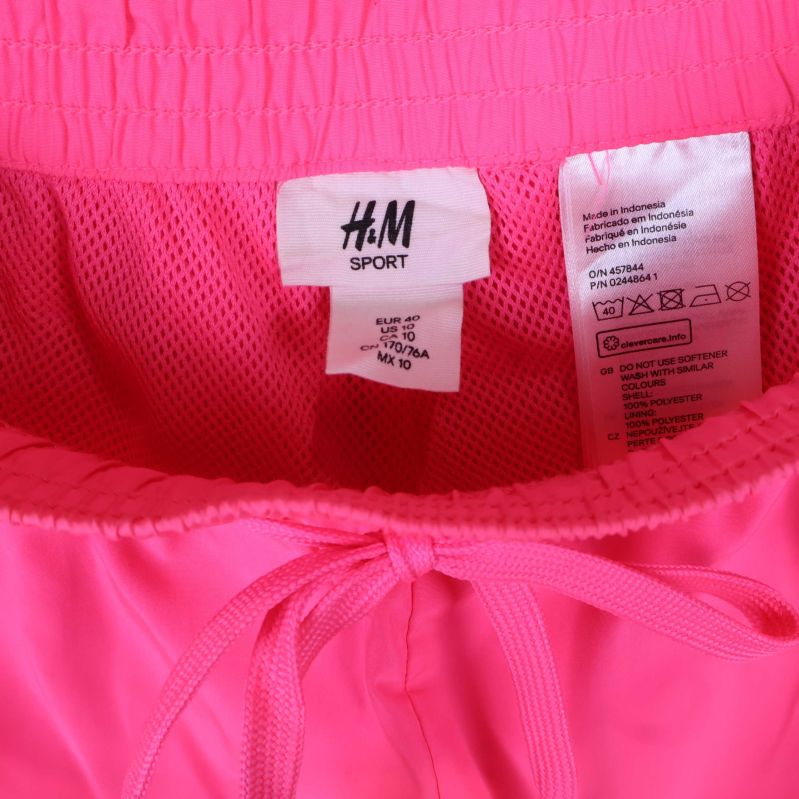 Närbild på H&M SPORT etikett på rosa shorts