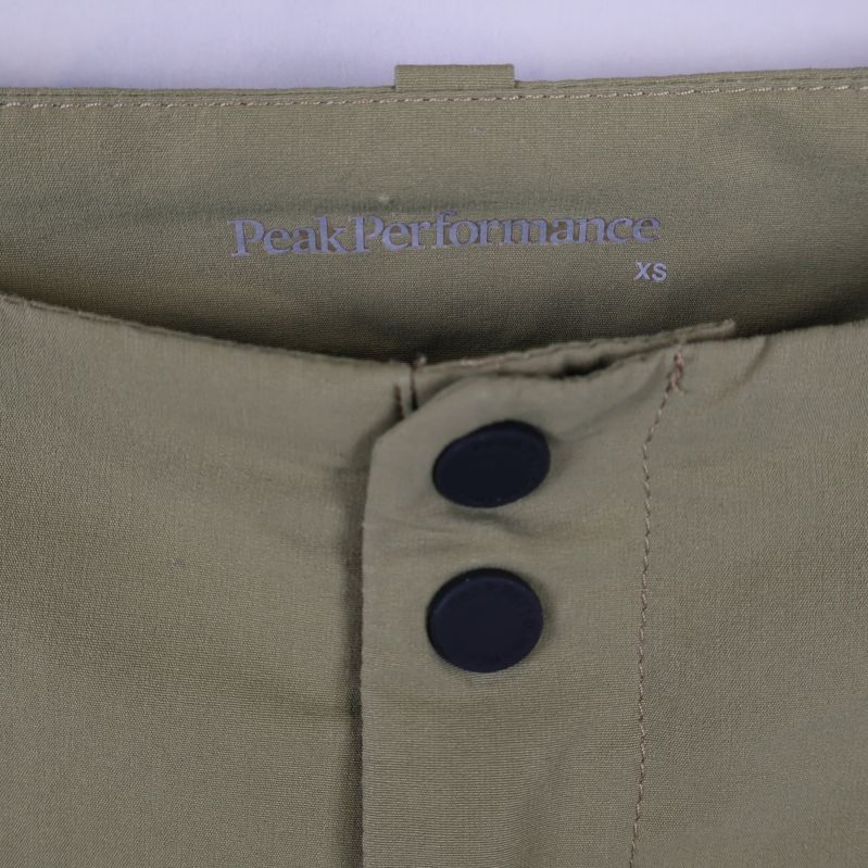 Närbild på Peak Performance-logo och storlek xs på byxlinningen
