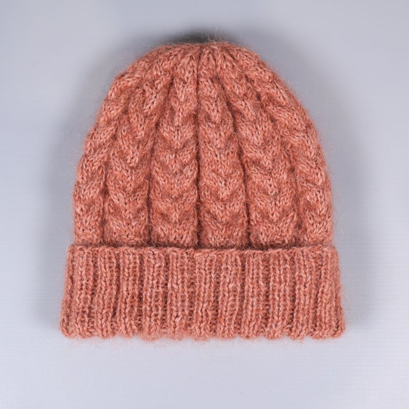 Stickad mössa i kabelmönster platt på grå bakgrund