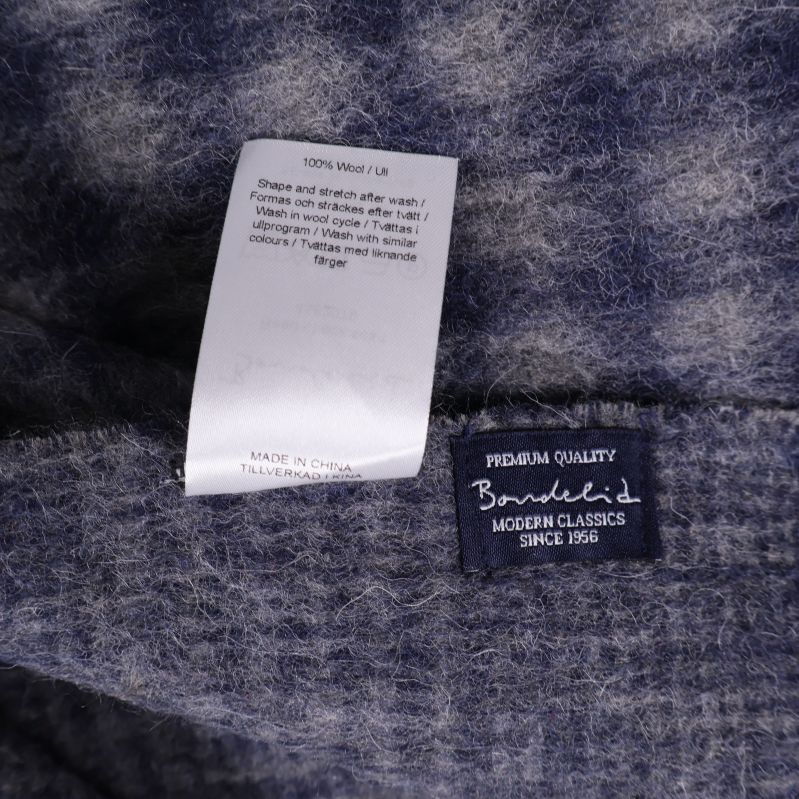 Materialinfo med texten 100% ull och varumärkesetikett