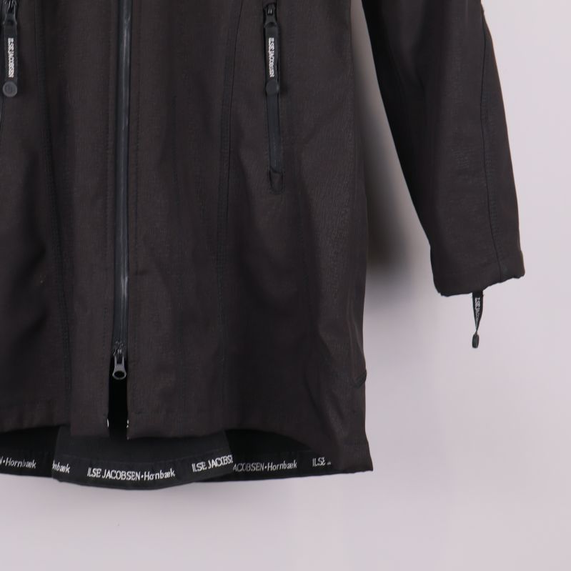 Regnjacka med öppen dragkedja och logoband längs nederkanten