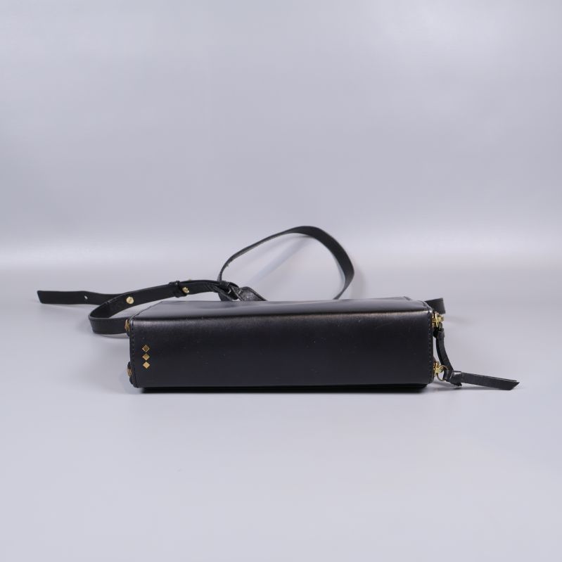 Undersida av svart axelremsväska med nitar