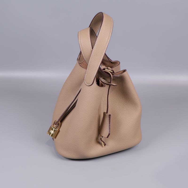 Beige bucketväska med handtag och guldfärgade detaljer