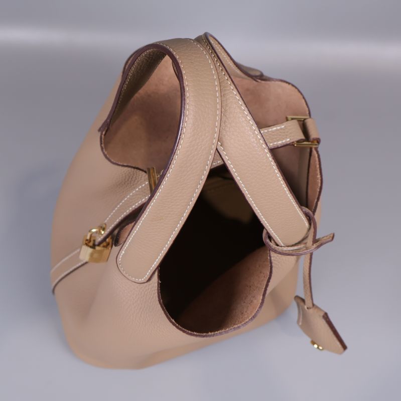 Öppen beige bucketväska med insyn till insidan och handtag