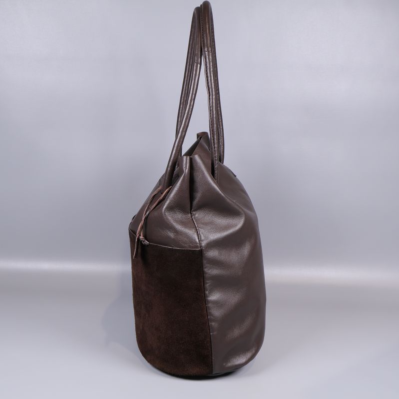 Sidan av brun bucketväska med axelband visas