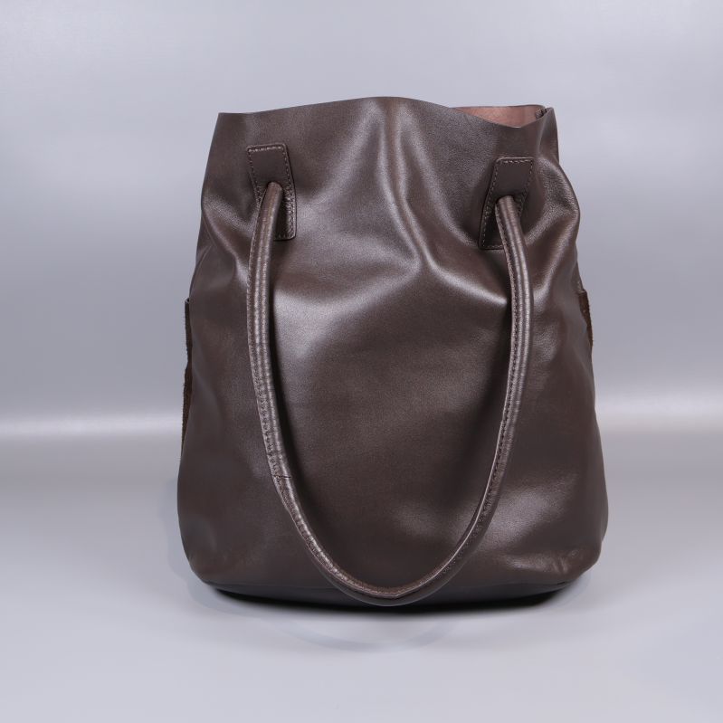 Framsidan av brun bucketväska med dubbla axelband