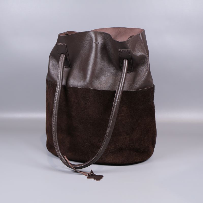 Brun bucketväska med axelband syns i helbild framifrån