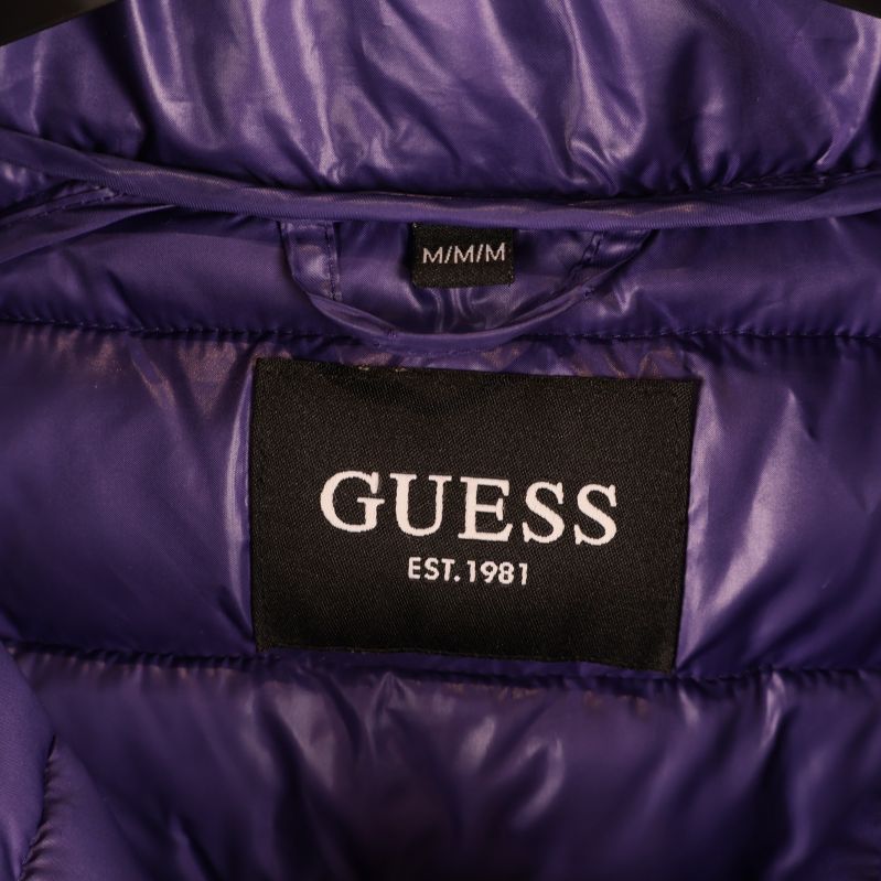 Närbild på svart GUESS-märke på jackans insida