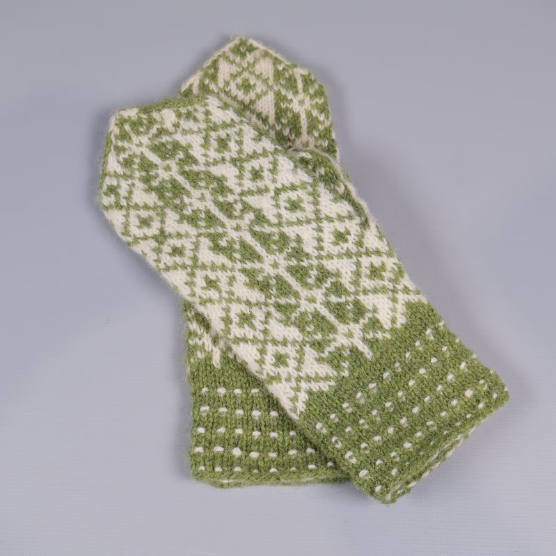 Gröna och vita tumvantar liggandes korslagda