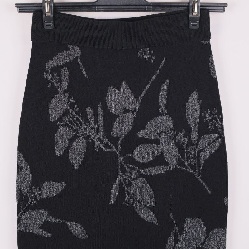 Närbild på midjan av svart kjol med grått bladmönster