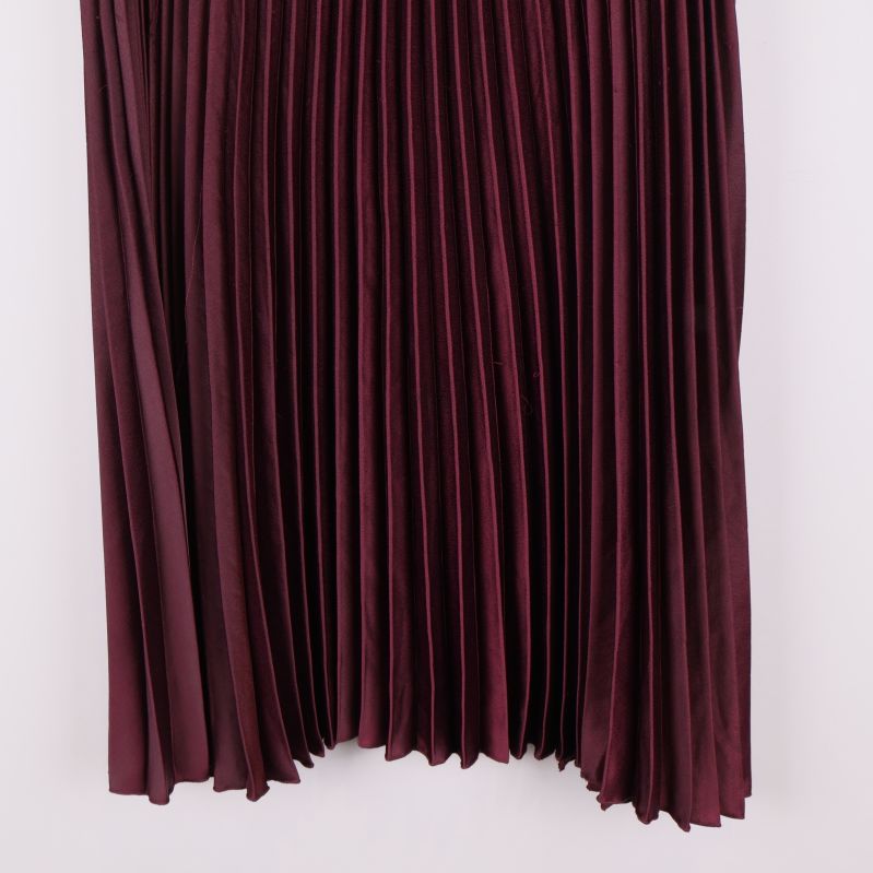 Detaljbild av nedre delen på vinröd plisserad kjol