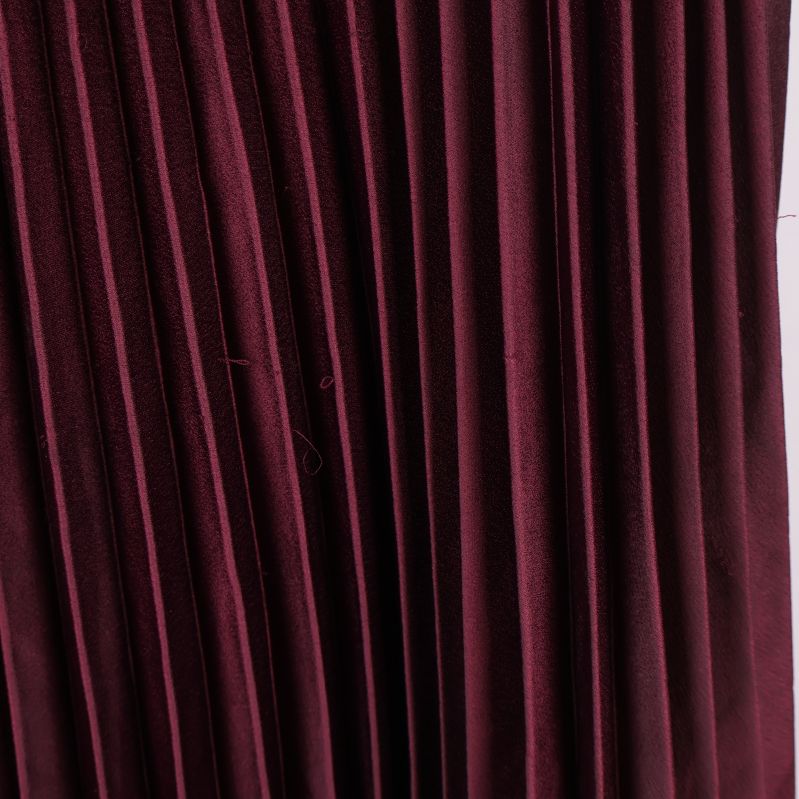 Närbild på tygstruktur och plissering av kjol