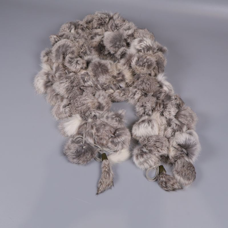 Grå pälssjal i bollformad design på grått underlag