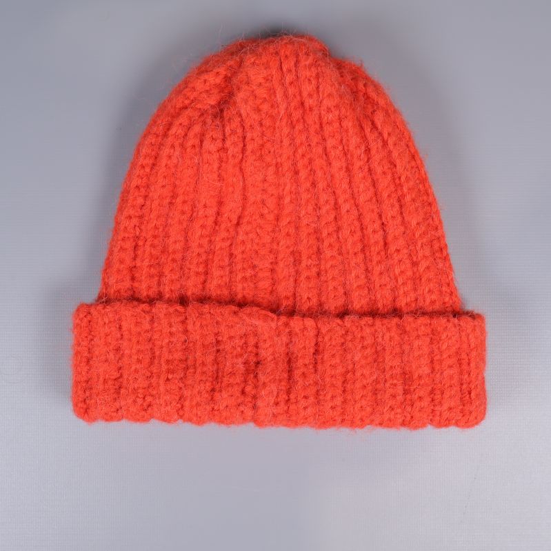 Orange stickad mössa sedd bakifrån mot grå bakgrund