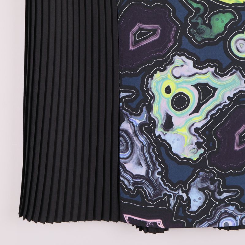 Nederkant på kjol med färgglad grafisk panel och svart plissering