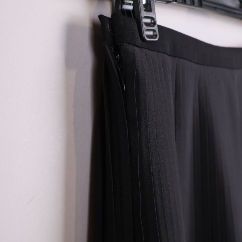 Närbild av sidosöm och plissering i svart tyg