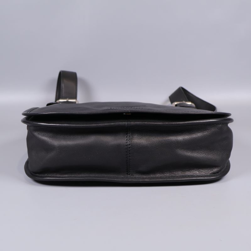 Svart läderväska sedd underifrån på ljus bakgrund