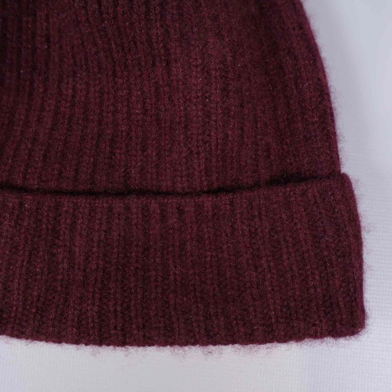 Närbild på mörkröd ribbstickad mössa med uppvik