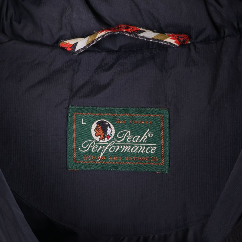 Närbild av Peak Performance-märke på grön etikett i kragen