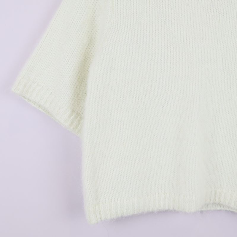 Närbild på ärmslut och nederkant på stickad tröja