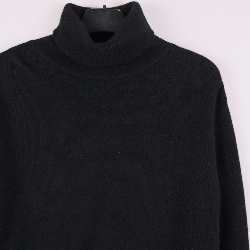 Närbild på polokrage och axel på svart tröja