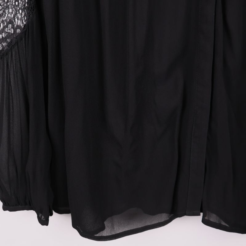 Närbild på nederkant av svart blus i tunt tyg