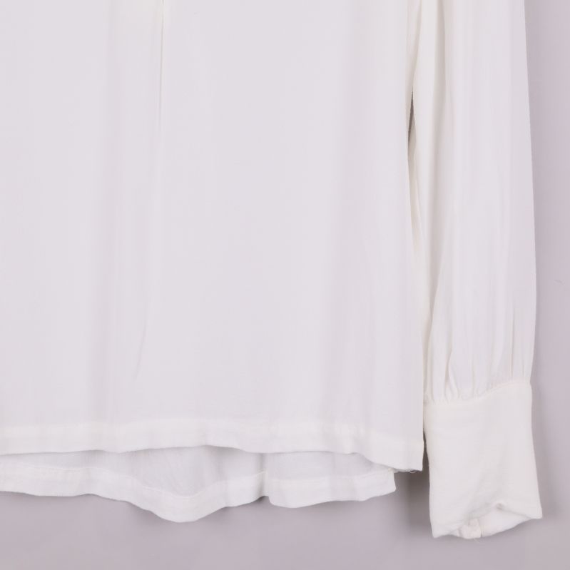 Närbild på nederkant och ärmslut på vit blus