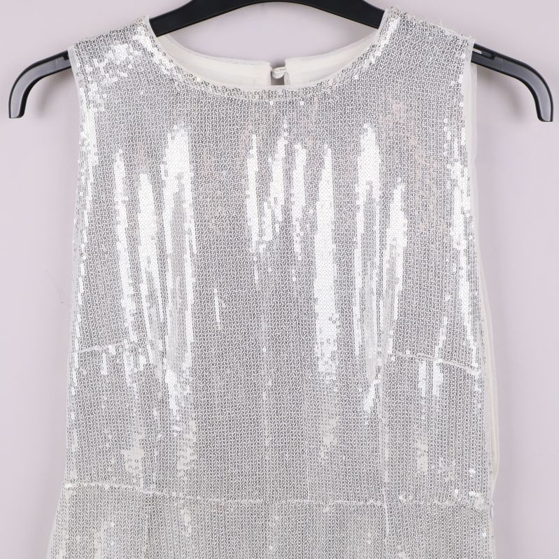 Övre delen av vit paljettklänning på galge