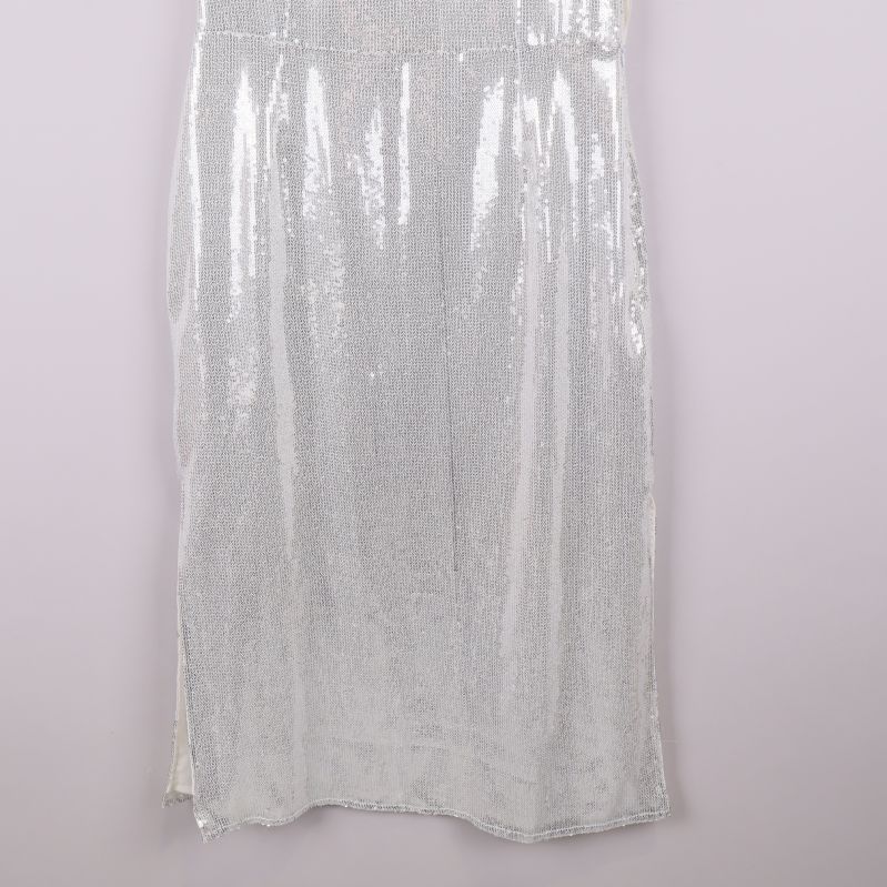 Nedre delen av vit paljettklänning med slits