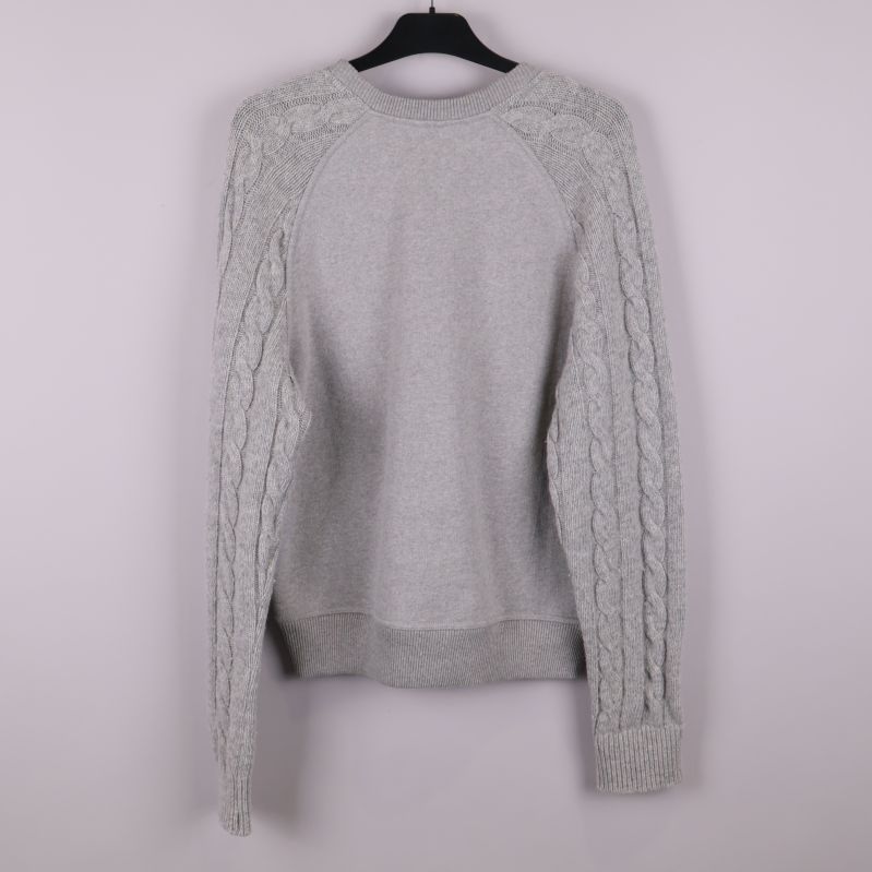 Baksidan av grå stickad tröja med flätade ärmar