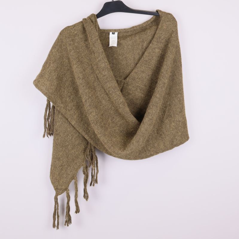 Poncho i stickat material draperad över galge framifrån