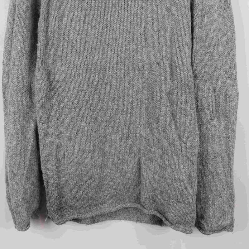 Närbild på nederkant och ärm grå stickad tröja