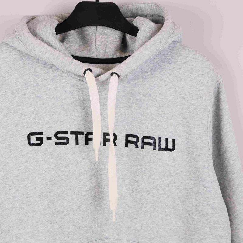 Närbild på huva och logga upptill på hoodie