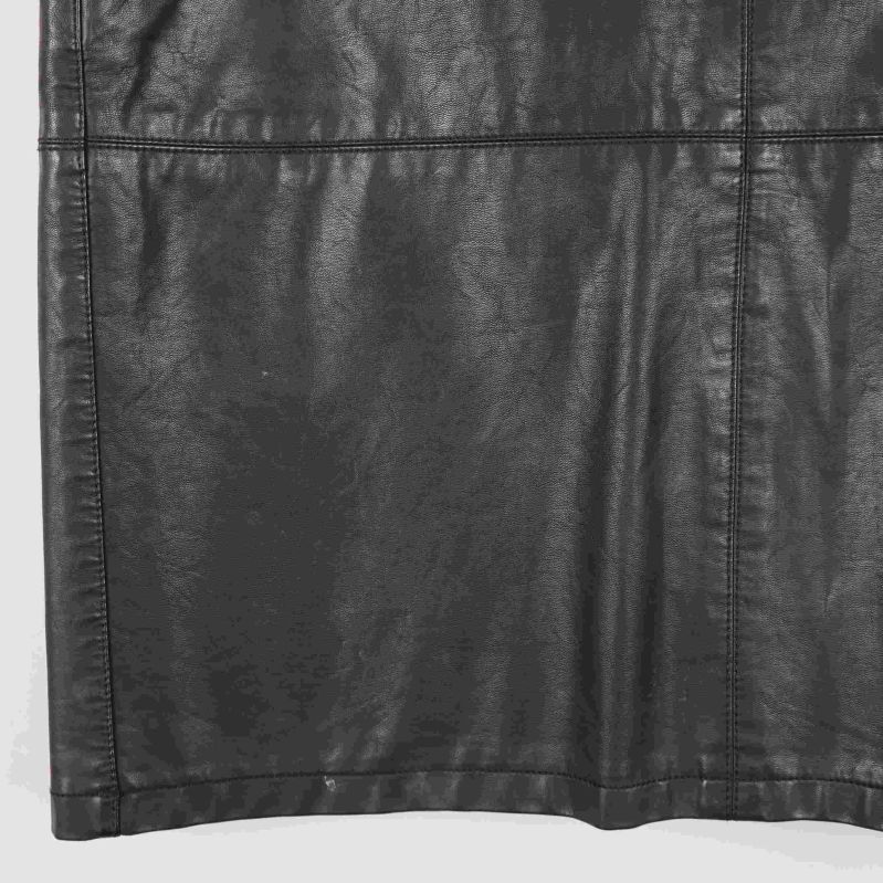 Nedre del av svart kjol i konstläder med synliga sömmar