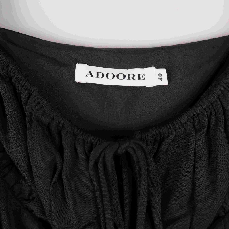 Närbild på ADOORE-logga och krage på svart tyg